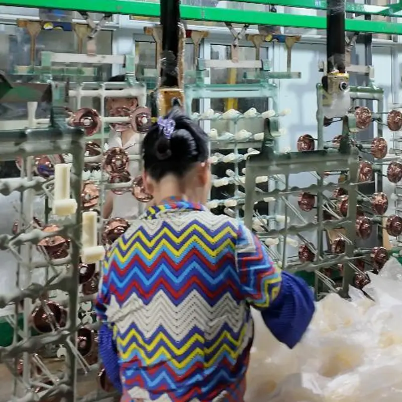 Factory worker picking and inspecting plated shower head parts from production rack