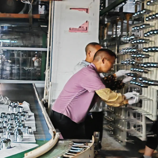 Jekare factory workers loading shower head components onto a chrome plating rack