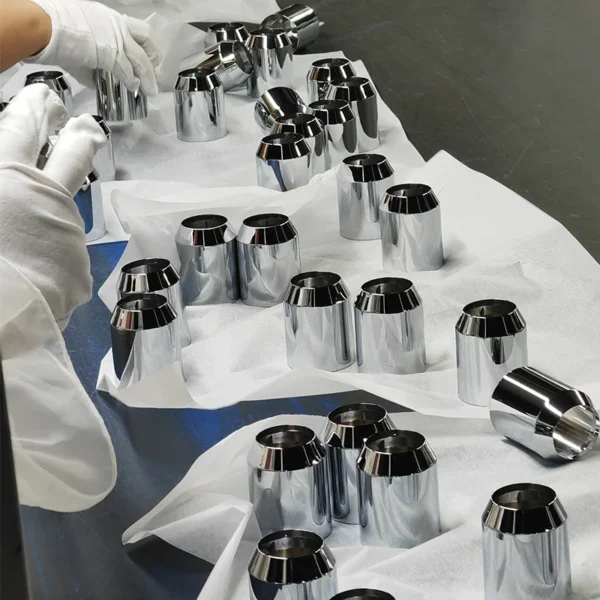 Worker inspecting chrome-plated bathroom components for surface quality
