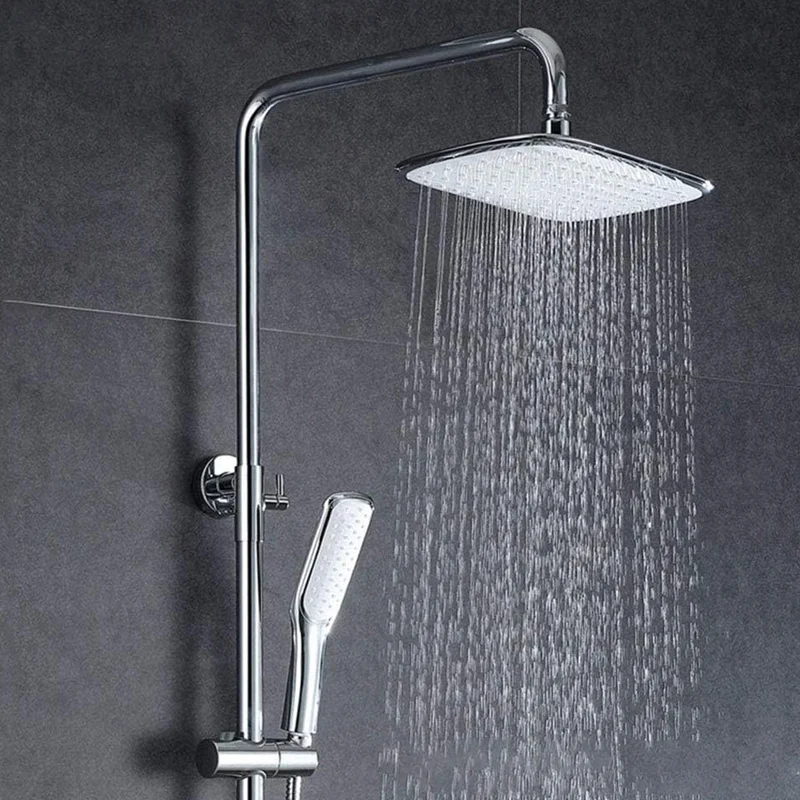 Full chrome shower column kit with square rain shower head and handheld sprayer spraying water on dark tile bathroom wall